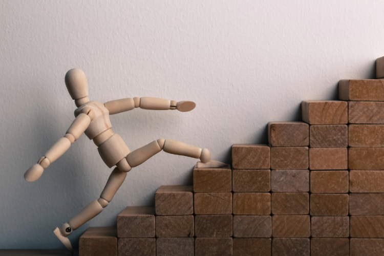 To represent growth and development, this image depicts a toy person climbing up block steps.